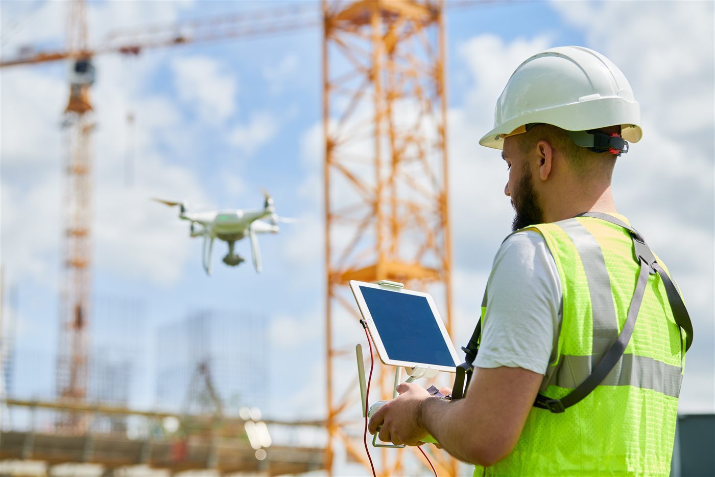 Operator monitoring an sUAS from a ground control station tablet on a job site